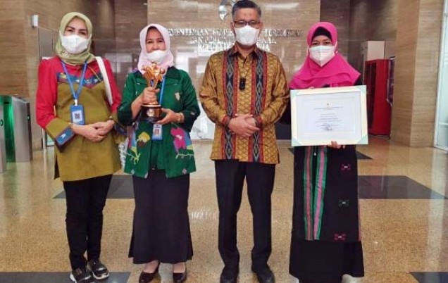 "Sulkarnain Kadir didampingi Plt. Kadis Pemberdayaan Perempuan menerima piala penghargaan Kota Layak Anak.